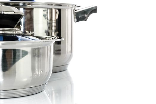 Culinary background - group of premium stainless steel pots and pans isolated on a white background with copy place.