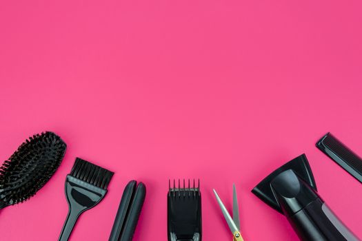 Hairdresser set with various accessories on a pink background with copy space