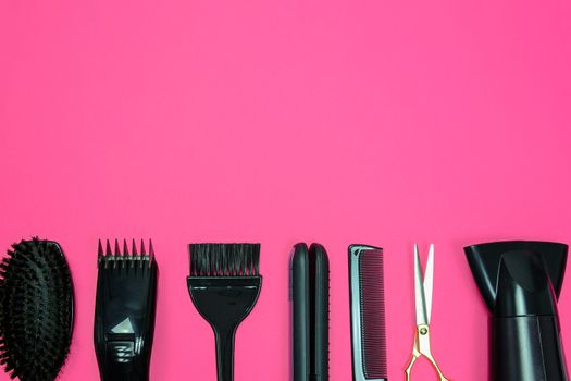 Hairdresser set with various accessories on a pink background with copy space