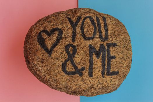 the writing you and me with a heart drawn on a stone,indicates the love promise of two lovers