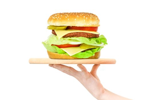 Concept of food serving service - female hand holding a wooden board with a big hamburger on a white background (mixed)
