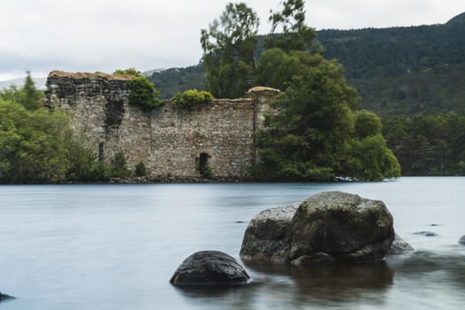 Old castle with a bridge with arcs and a river in a sunny day in Scotland, Cairngorms