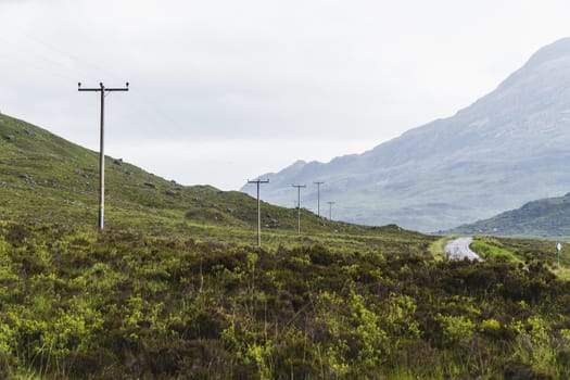 Landscape of mountains, a road and telephone posts in Scotland