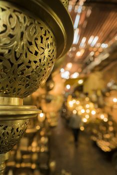 Beautiful golden smith of a lamp hanging in Marrakesh souk with people walking