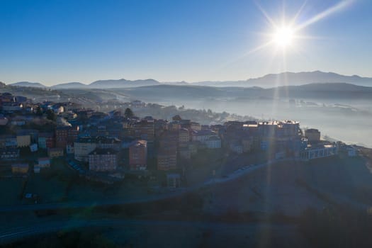 Aerial shot of a town in northern spain with fog and sun