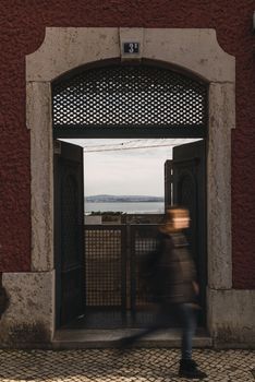 old lisbon door with sea views blurry girl crossing ancient red building