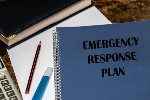 ERP as an emergency response procedure, the text is written on a blue book lying on the office Desk among work papers