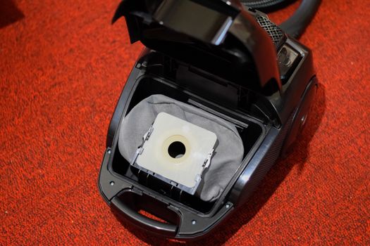A vacuum cleaner with a set of brushes and bags. A vacuum cleaner on the red carpet.