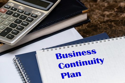 The text of the business continuity plan is written on a white sheet lying on the office Desk. Concept BCP