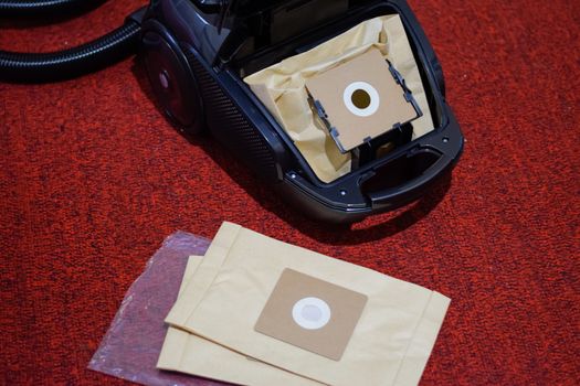 A vacuum cleaner with a set of brushes and bags. A vacuum cleaner on the red carpet.