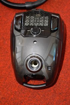 A vacuum cleaner with a set of brushes and bags. A vacuum cleaner on the red carpet.