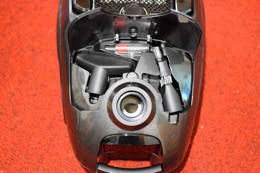 A vacuum cleaner with a set of brushes and bags. A vacuum cleaner on the red carpet.