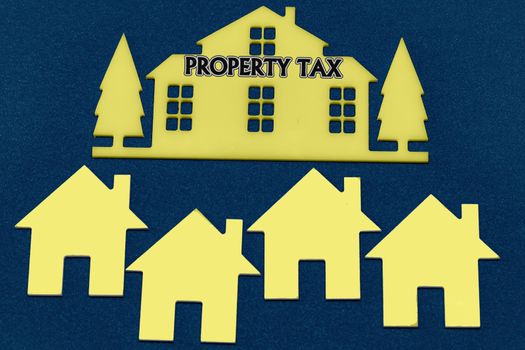 Miniature houses on a blue paint background and text Property Tax. Business, finance, saving money, property ladder or mortgage loan concept