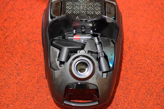 A vacuum cleaner with a set of brushes and bags. A vacuum cleaner on the red carpet.