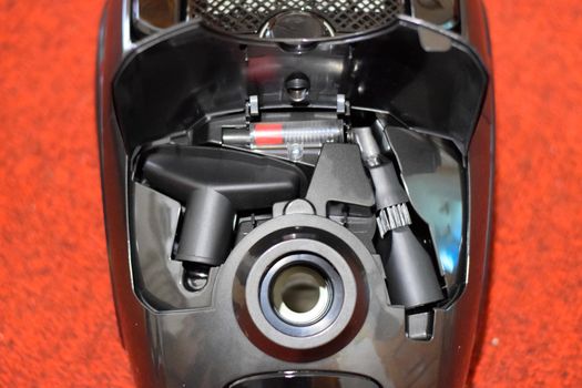 A vacuum cleaner with a set of brushes and bags. A vacuum cleaner on the red carpet.