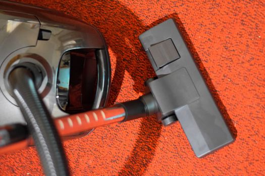 A vacuum cleaner with a set of brushes and bags. A vacuum cleaner on the red carpet.