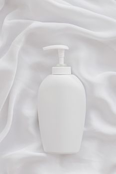 Blank label cosmetic container bottle as product mockup on white silk background, hygiene and healthcare