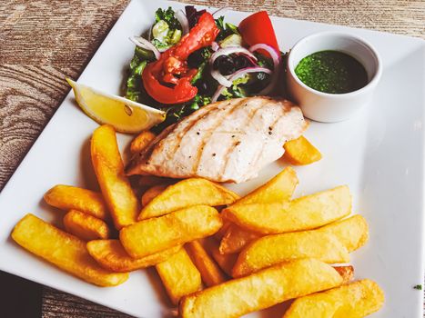 Grilled chicken, french fries and salad for lunch, served meal