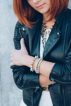 red-haired girl in a black jacket and blue glasses on a gray road