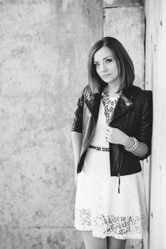 red-haired girl in a black jacket and blue glasses on a gray road