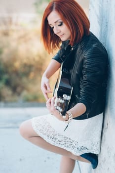 musician young girl with red hair with an acoustic guitar