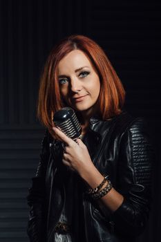 young red-haired girl in a white dress and a black leather rocker jacket sings emotionally into the microphone