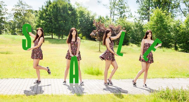 four young pretty smiling girls holding letters with the word sale outdoor on sunny summer day