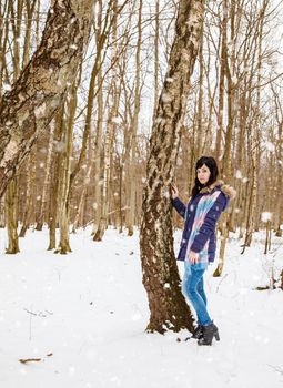 pretty young woman walking in the park on cold snowy winter day