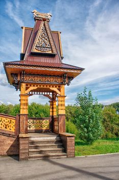 wooden pergola decorated with carvings on sunny summer day