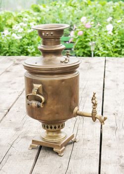 brass old samovar on a wooden table closeup outdoor