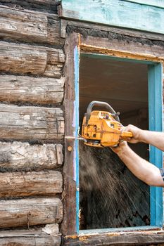 chainsaw man sawing a window in the repair of the house closeup