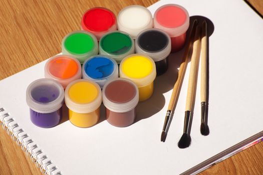 set of watercolor paints and brushes with white notepad