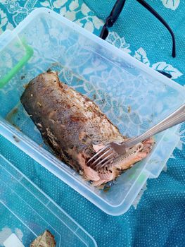 Baked pink salmon in a plastic food container. Eating fish.