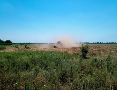 The combine removes the barley on the field and dusts hard.