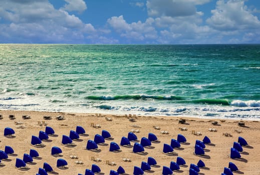 Lines of blue beach shelters by a stormy sea