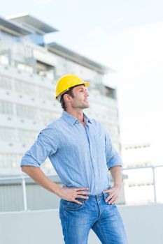 Thoughtful male architect with hands on hips outdoors