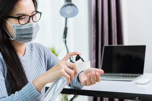 Asian young business beautiful woman wearing face mask protective working from home office with laptop computer desk he quarantines disease coronavirus and cleaning hands by sanitizer alcohol gel pump