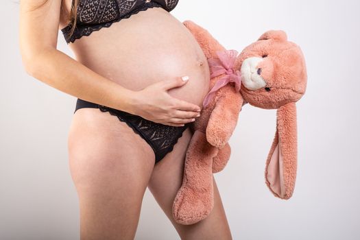 Close-up pregnant woman's belly with Hare toy. Beautiful pregnant woman. Pregnancy, parenthood, preparation and expectation concept