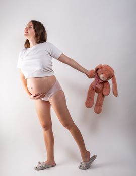 Close-up pregnant woman's belly with Hare toy. Beautiful pregnant woman. Pregnancy, parenthood, preparation and expectation concept