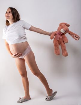 Close-up pregnant woman's belly with Hare toy. Beautiful pregnant woman. Pregnancy, parenthood, preparation and expectation concept