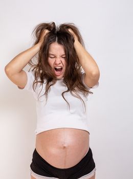 The young beautiful pregnant woman experiences strong emotions on a white background.