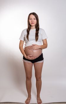 The young beautiful pregnant woman experiences strong emotions on a white background.