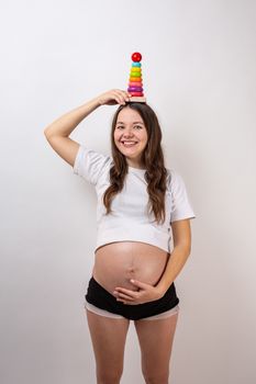 Pregnant girl with a wooden rainbow pyramid for children.