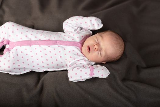 Little newborn baby boy sleeps in darck background.