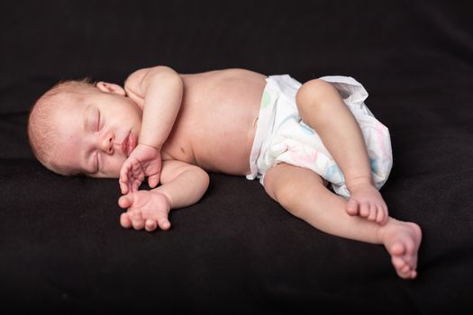 Little newborn baby boy sleeps in darck background.