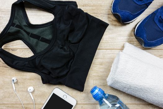 Fitness activity concept - flat lay of some personal sport accessories for woman on a wooden background.