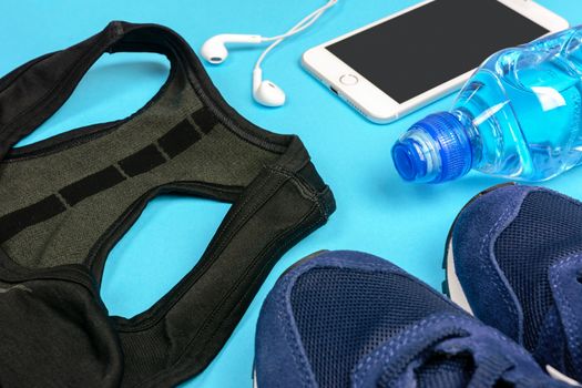 Fitness activity concept - composition of some personal sport accessories for a runner woman on a blue background.