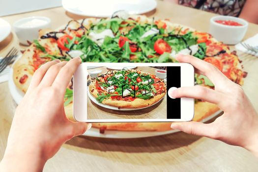 Composite image of making pizza photos on a smartphone - woman's hands holding mobile phone and touching shutter button on the screen.