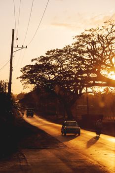 Road traffic at sunset, Cuba. Buses, cars and motorcycles.