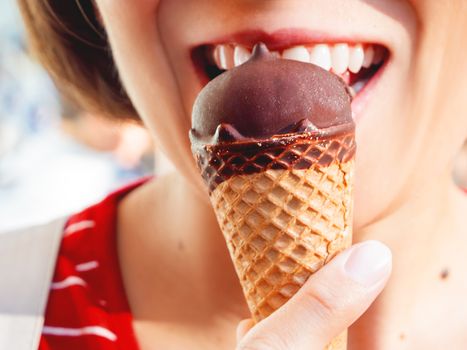 Woman in red shirt is eating ice-cream. Close up photo of cold dessert. Summer fun.